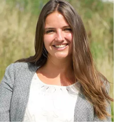 A woman with brown hair, smiling.